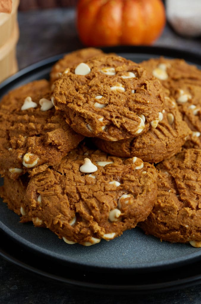 Pumpkin cookies stacked on top of each other on a plate.