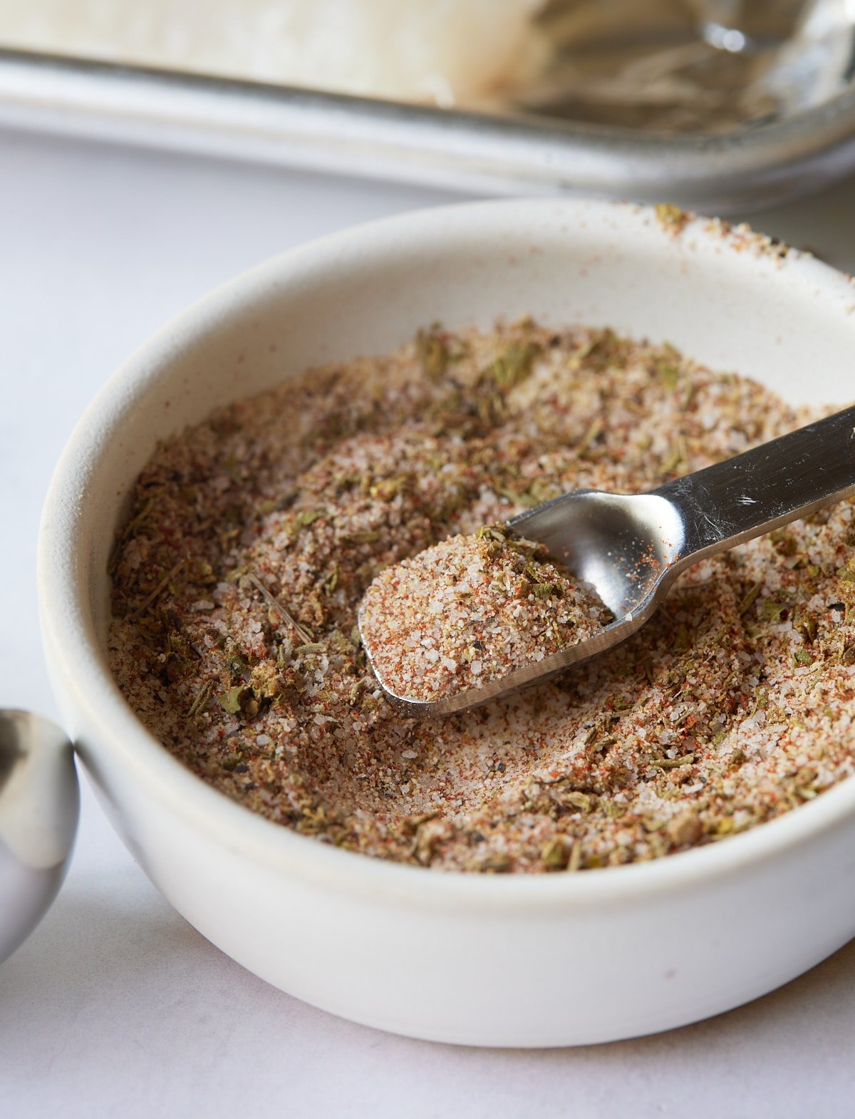 Fish seasoning in a white bowl with a small measuring spoon.