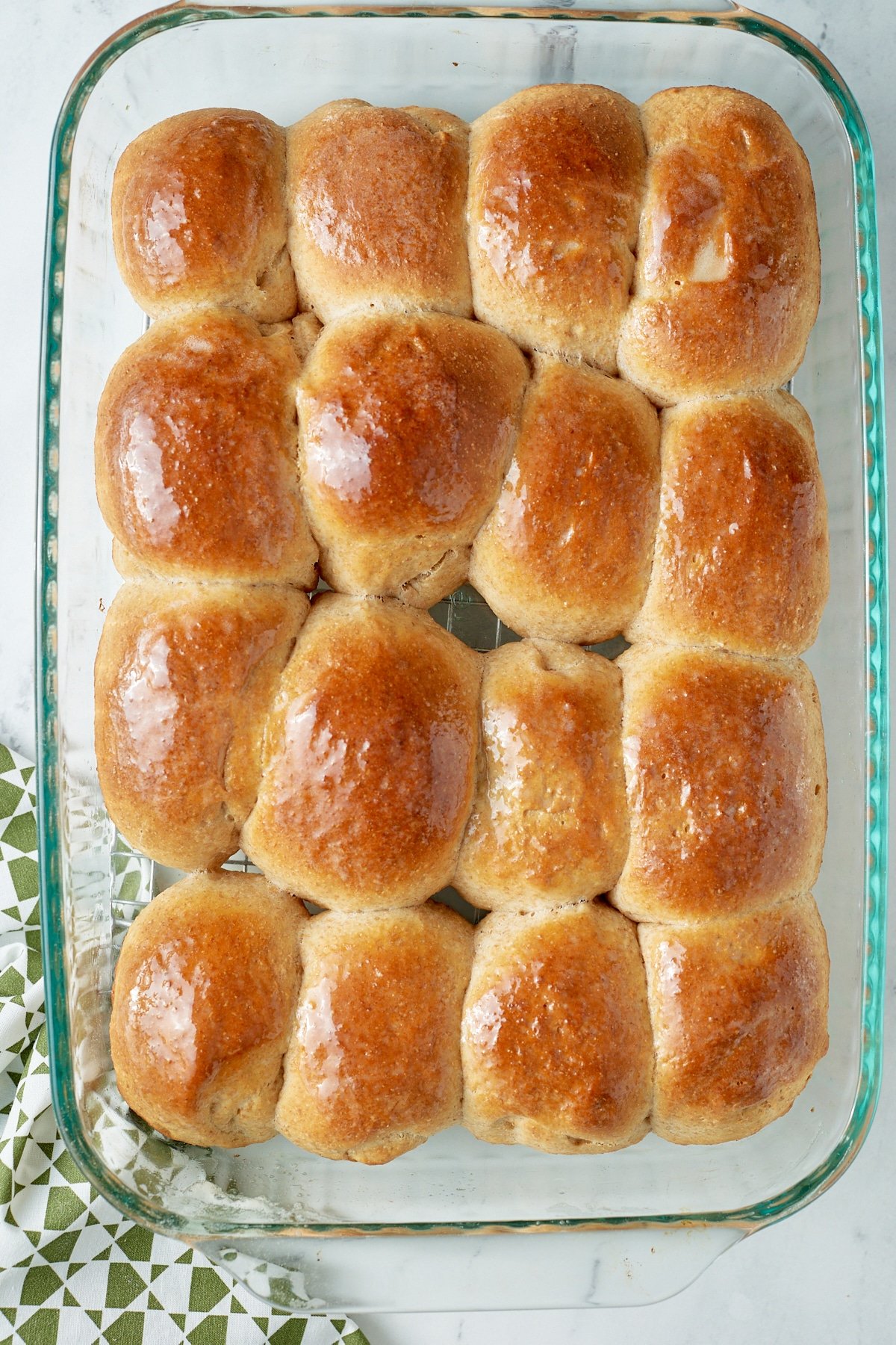 Baked honey whole wheat dinner rolls in a glass baking dish.