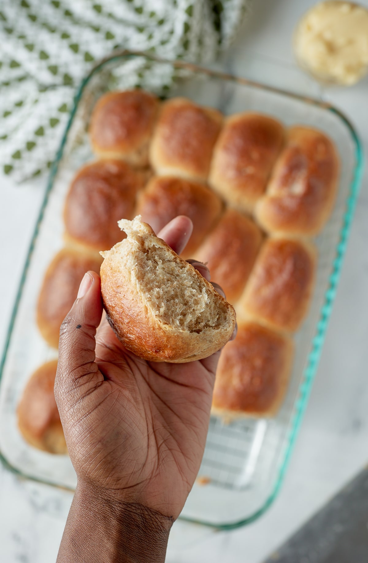 A hand holding a baked dinner roll.