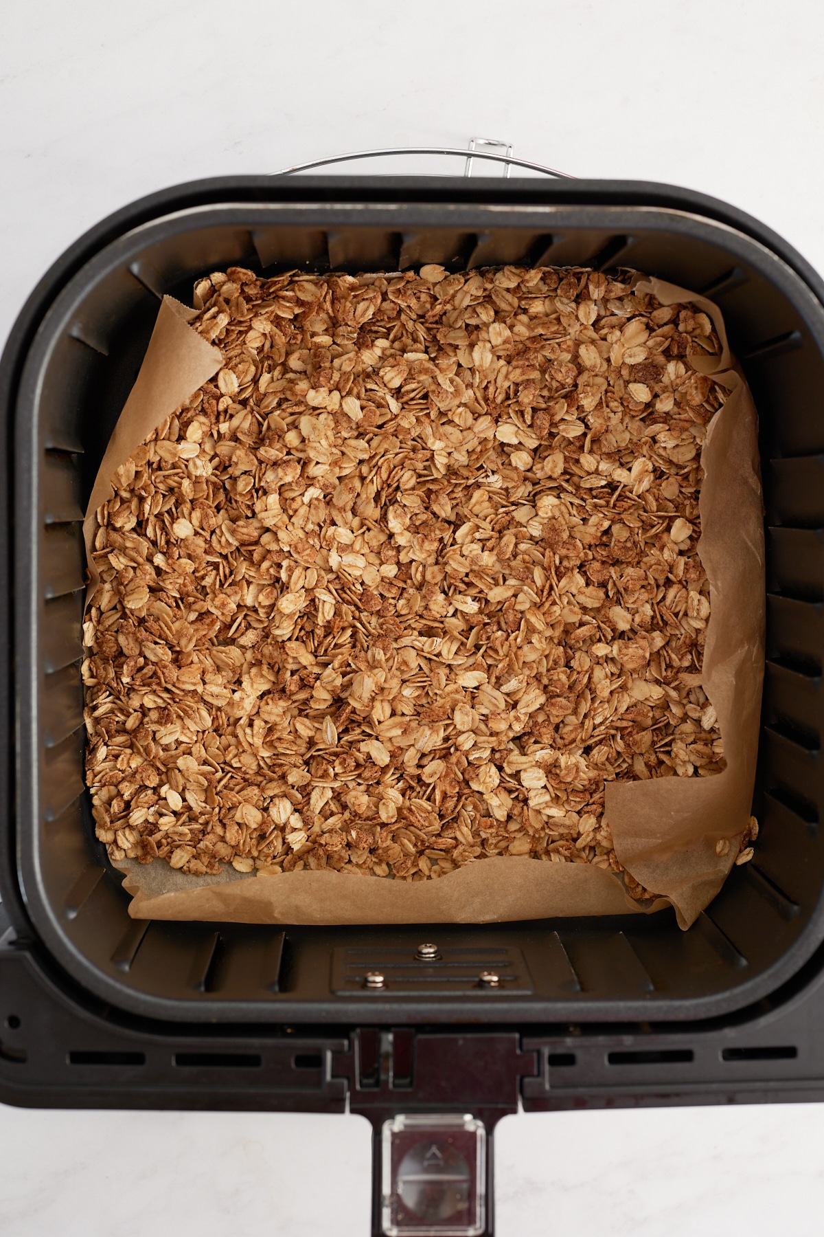 The cooked granola in an air fryer basket.