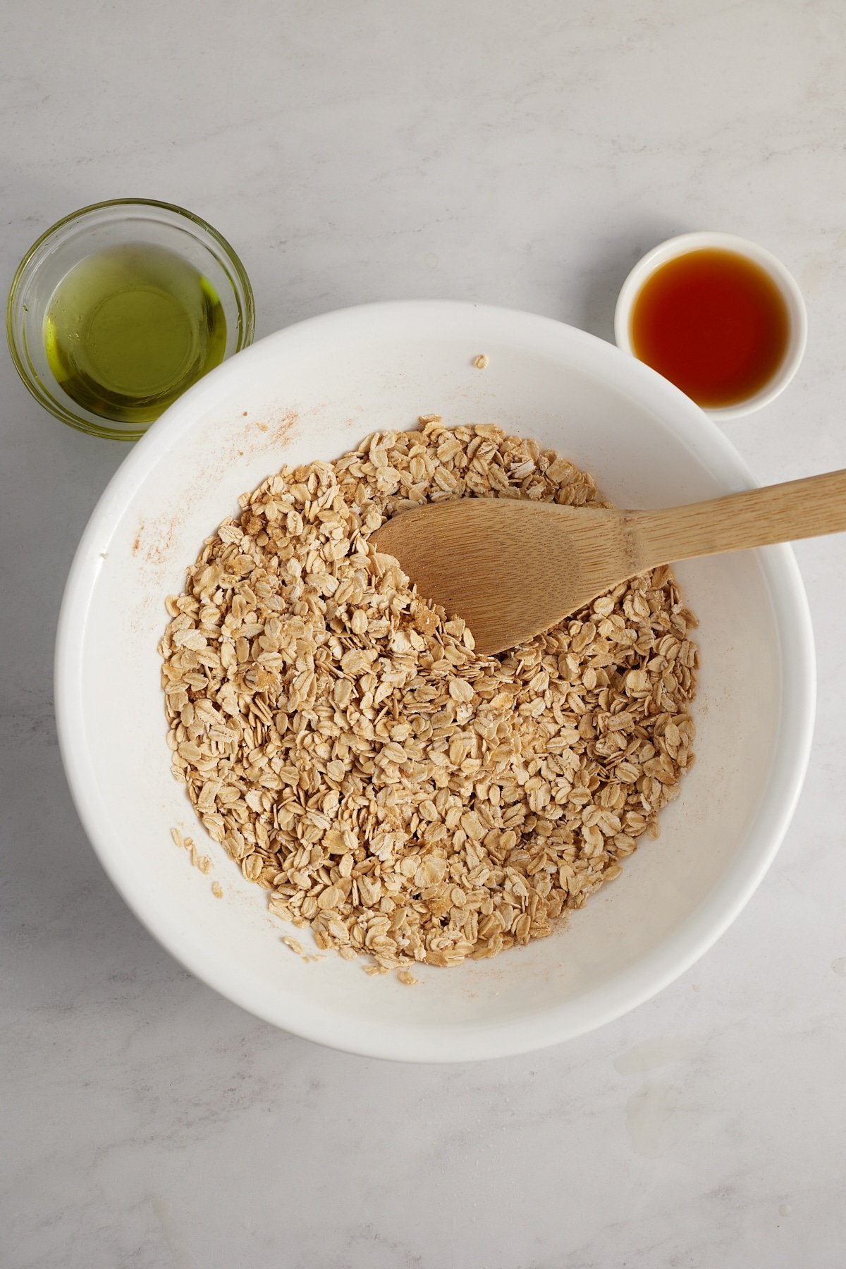 The dry granola ingredients in a bowl with a spoon.