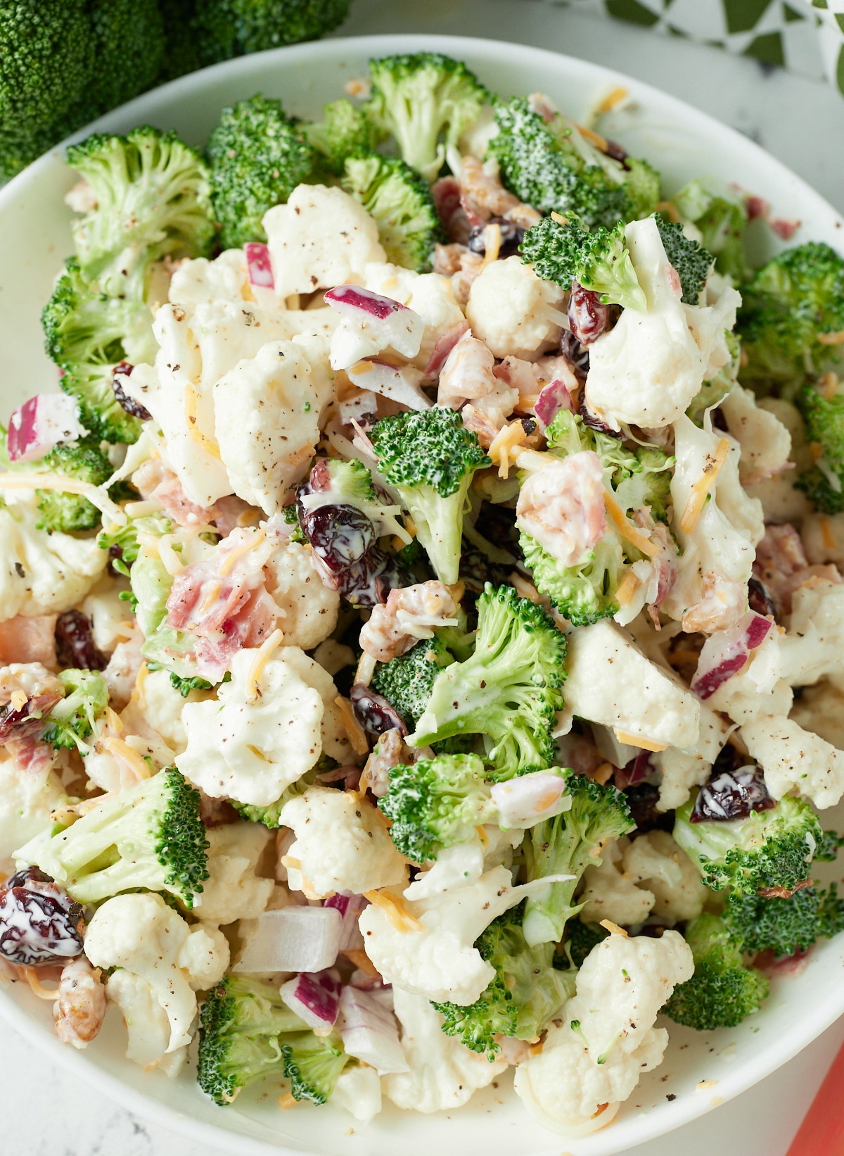 Overhead shot of broccoli cauliflower salad in a white bowl.