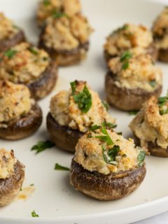 Baked cream cheese stuffed mushrooms garnished with fresh parsley.