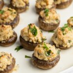 Cream cheese stuffed mushrooms served on a white plate.
