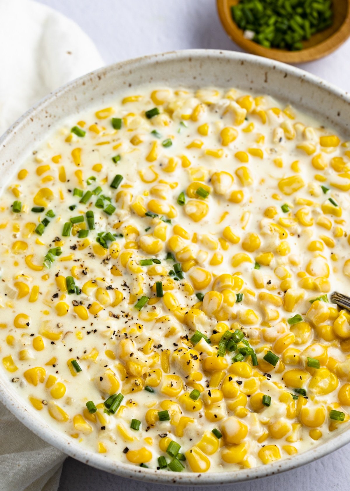 Creamed corn in a skillet with fresh herb garnish.