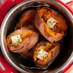 Cooked sweet potatoes in an Instant Pot, split open and topped with butter and fresh herbs.