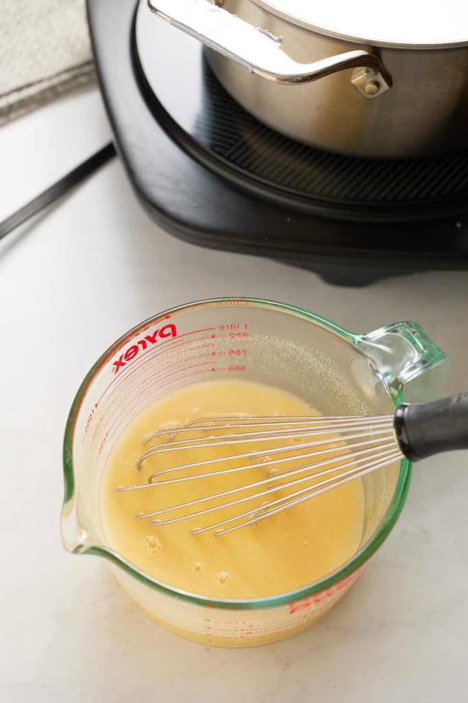 cornmeal and water in measuring cup with whisk sticking out