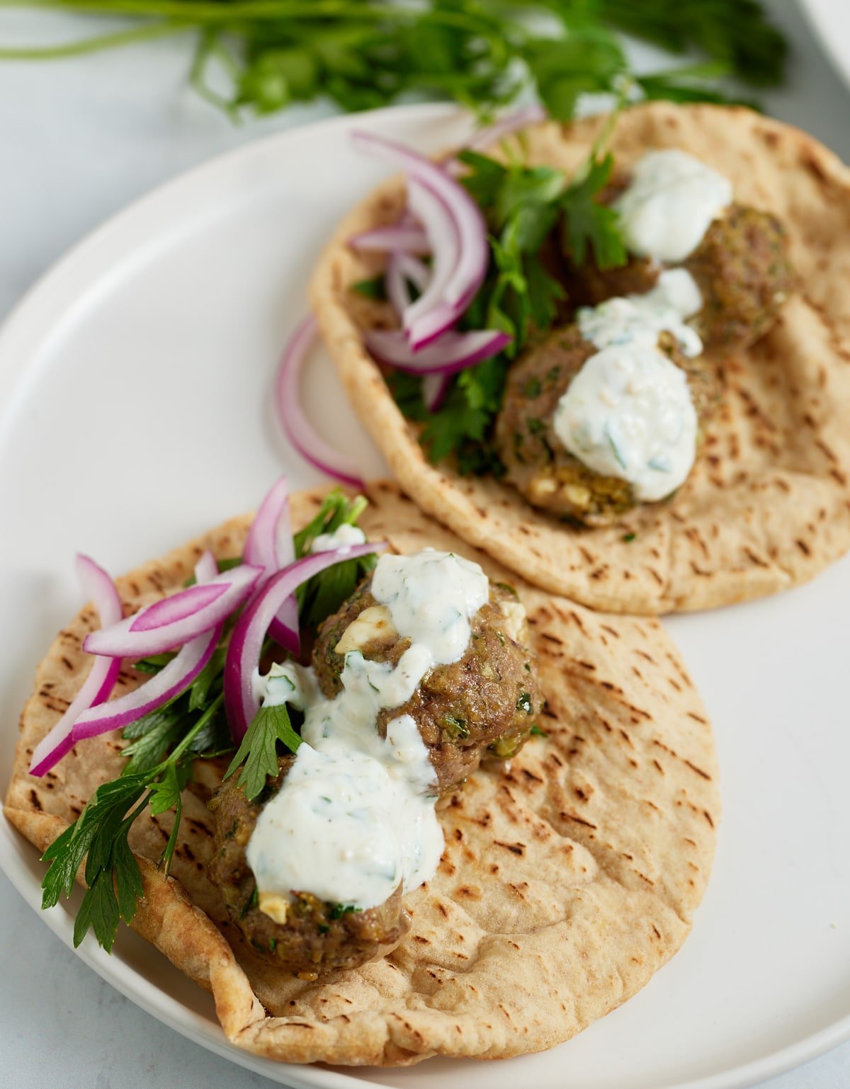 close up of lamb meatballs on pita bread and toppings