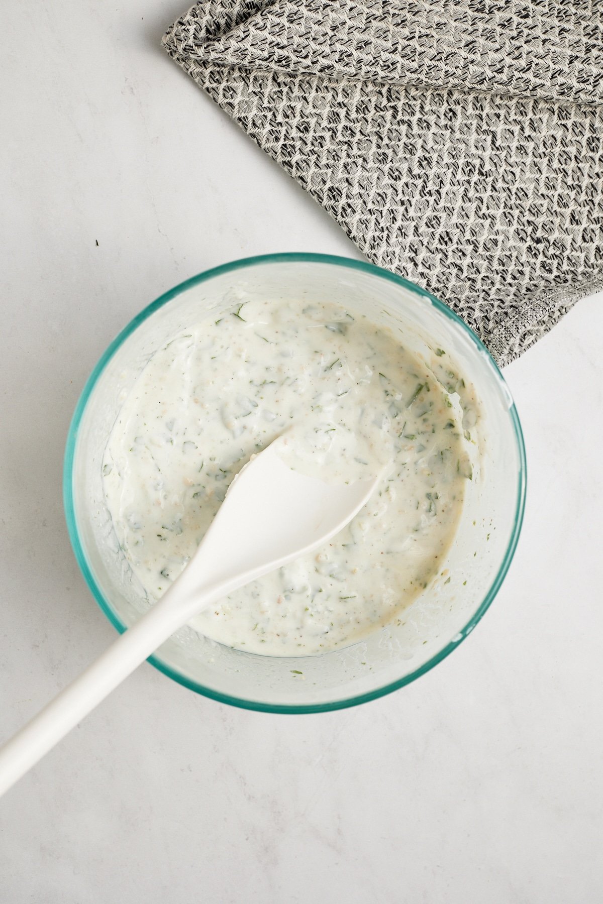 yogurt sauce in glass bowl with white spoons ticking out