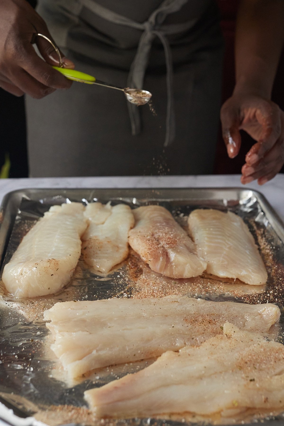 Sprinkling seasoning of fish fillets.