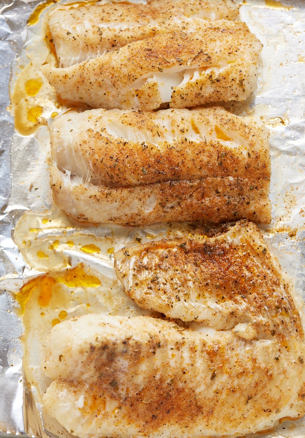 Oven baked fish fillets on a foil lined baking sheet.