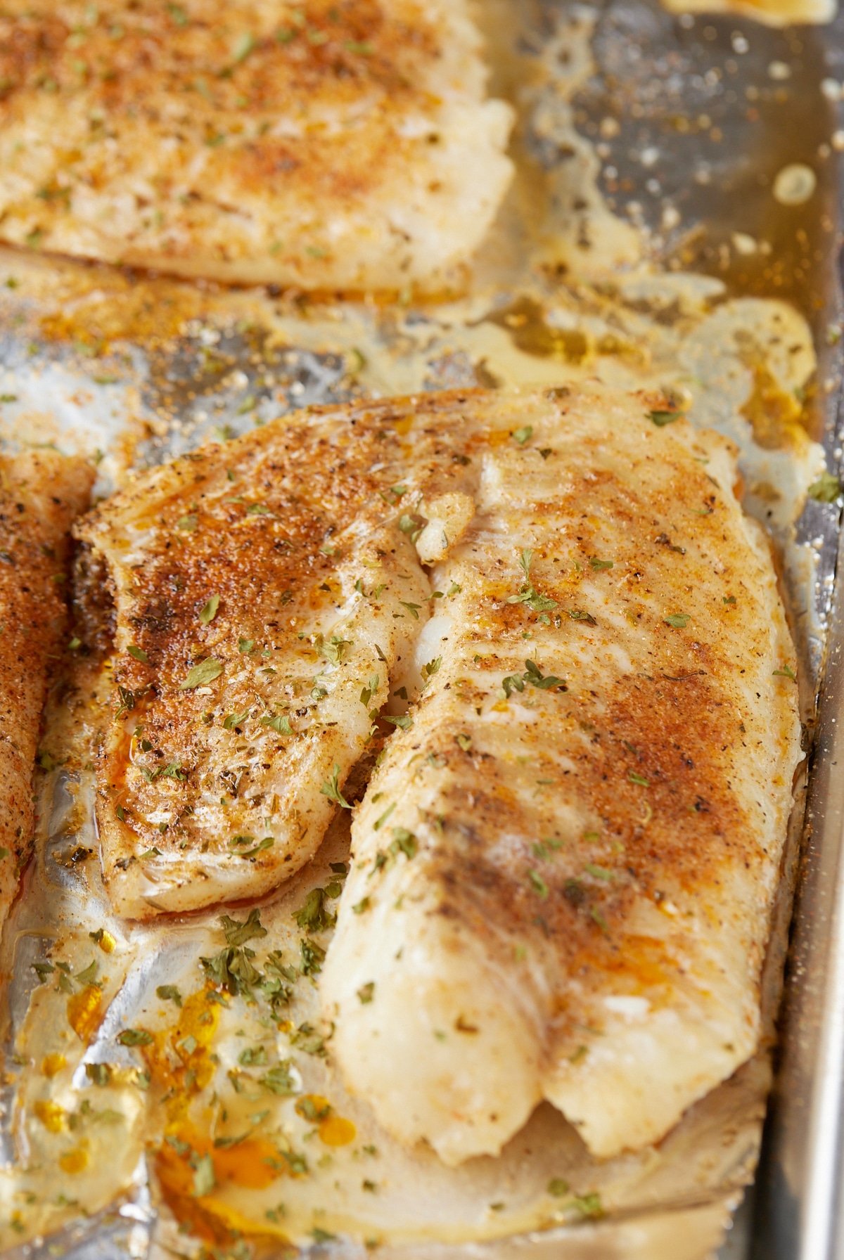 Two baked fish fillets on a baking sheet ready to serve.