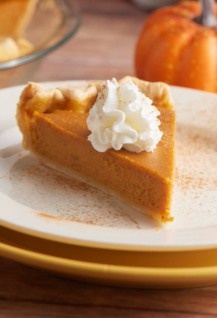 A slice of homemade pumpkin pie with whipped cream.