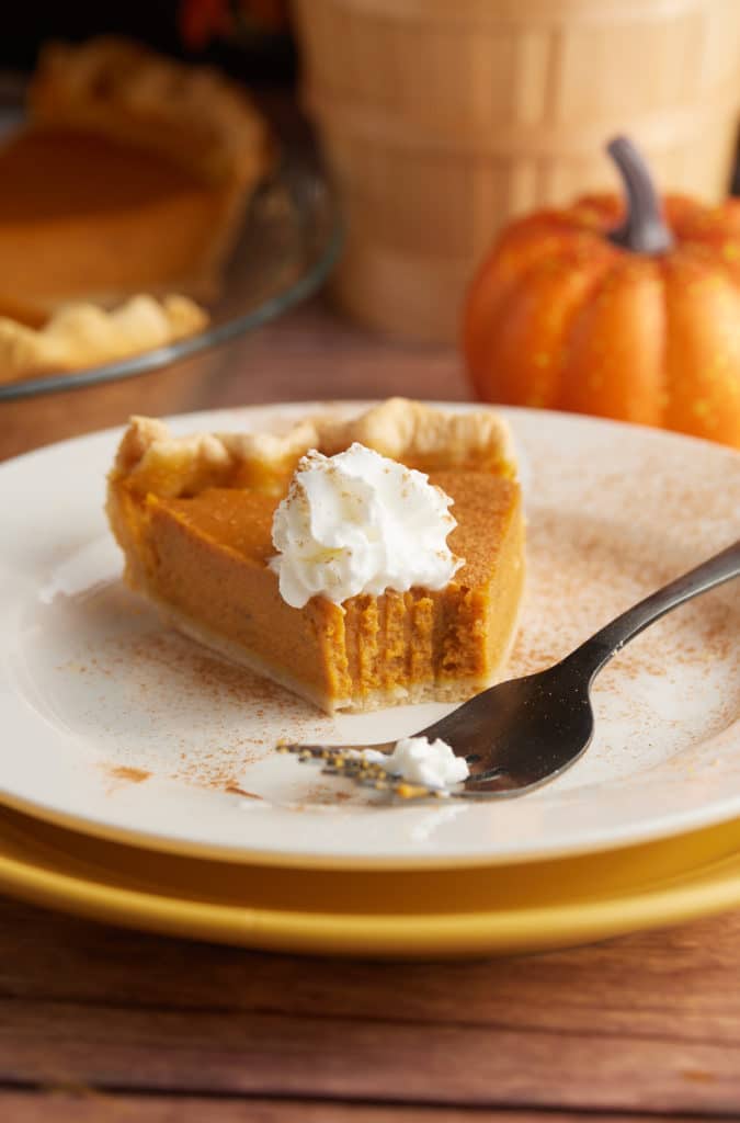 A slice of pupkin pie on a plate with a fork.