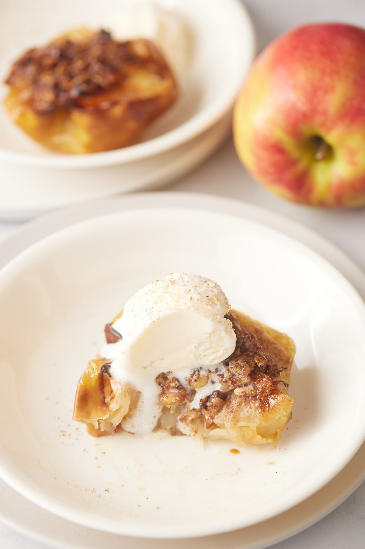 An apple served in a white bowl and topped with ice cream.