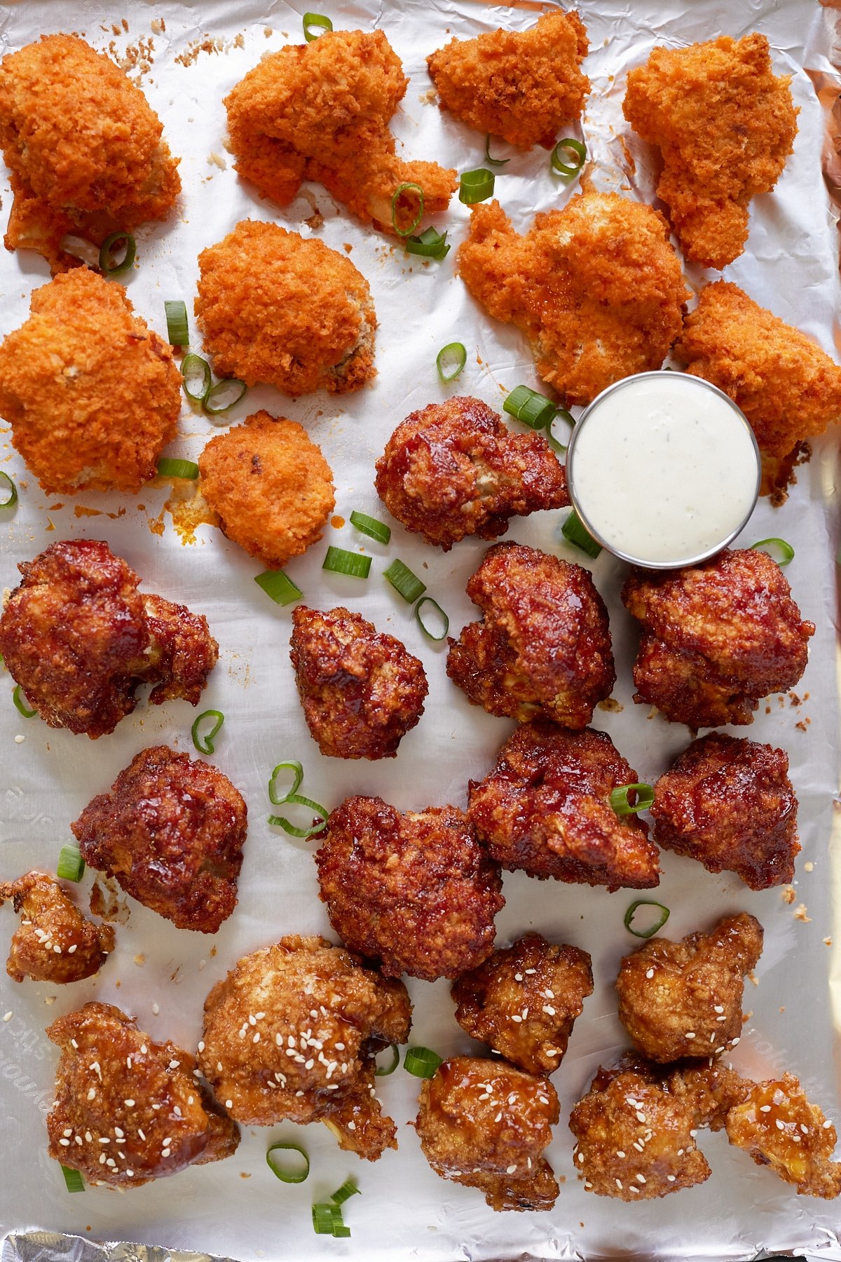 sauced cauliflower wings on baking sheet lined with foil