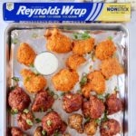 cauliflower wings on sheetpan lined with foil pan with cauliflower, celery, and box of reynolds wrap on top
