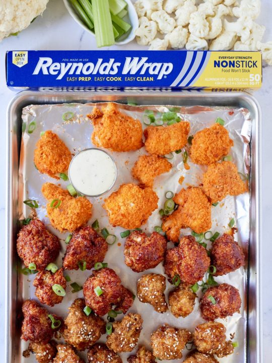 cauliflower wings on sheetpan lined with foil pan with cauliflower, celery, and box of reynolds wrap on top
