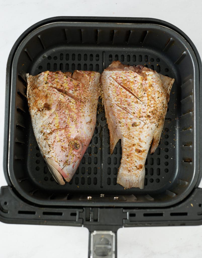 seasoned fish in air fryer basket before cooking