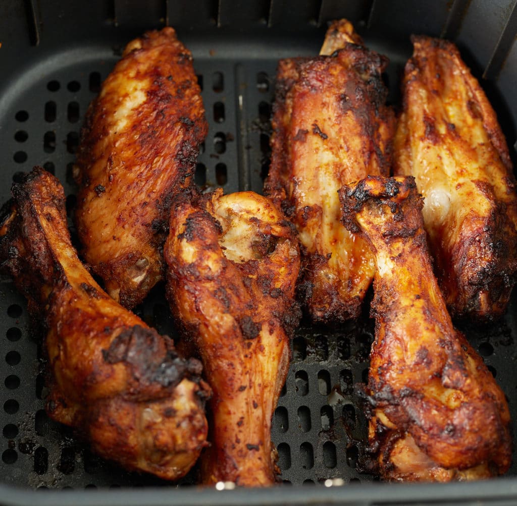 Six cooked turkey wings in an air fryer basket.