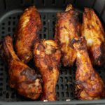 Six cooked turkey wings in an air fryer basket.
