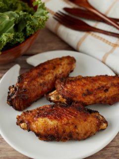 Three air fryer turkey wings on a white pate.