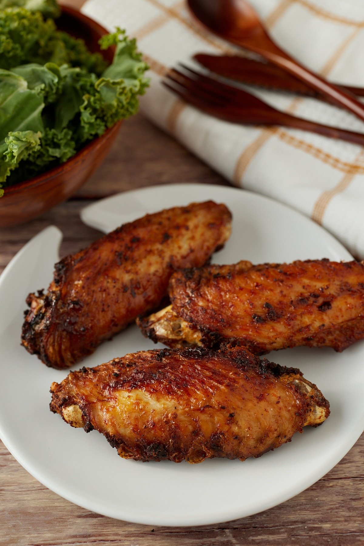 Three air fryer turkey wings on a white pate.