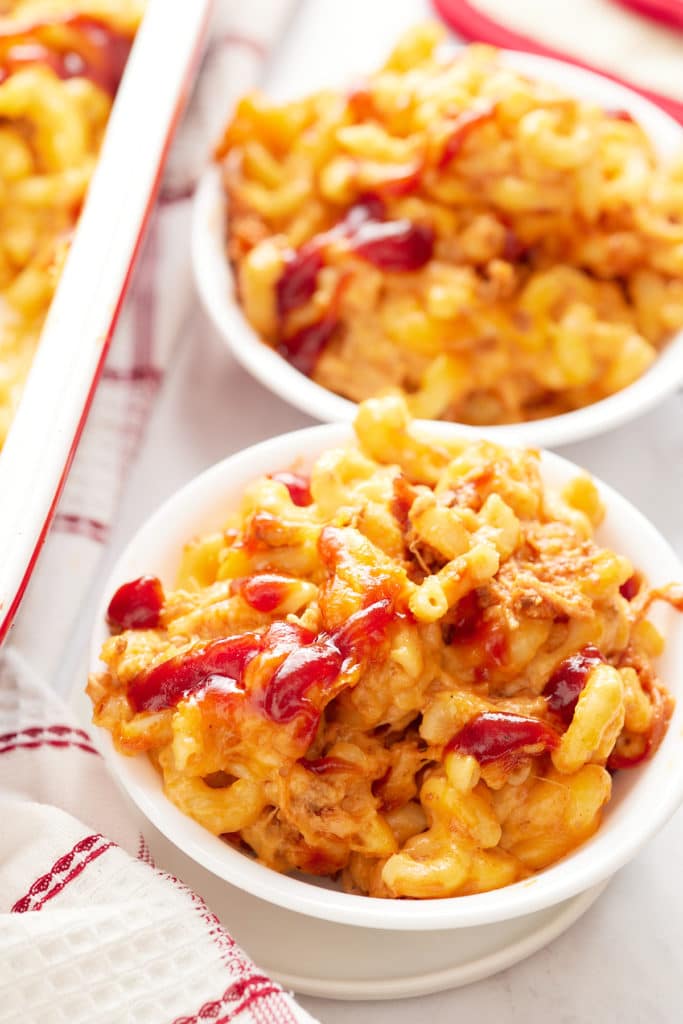 Two bowls of mac and cheese topped with BBQ sauce.