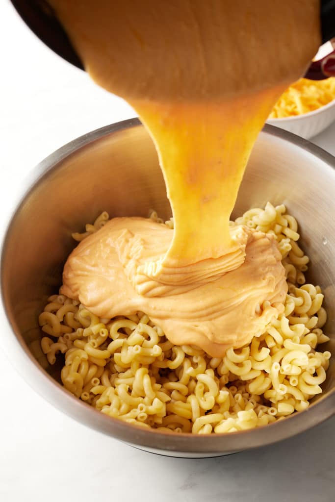 The sauce being poured over the macaroni.