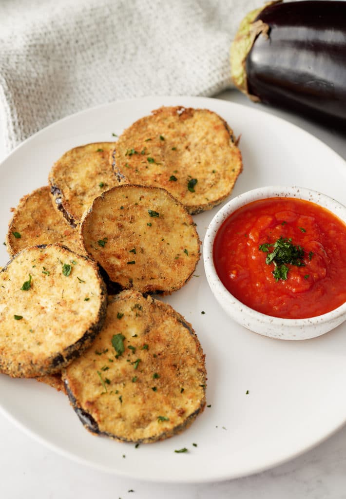 Crispy air fryer egg plant on a plate served with a marinara dip.