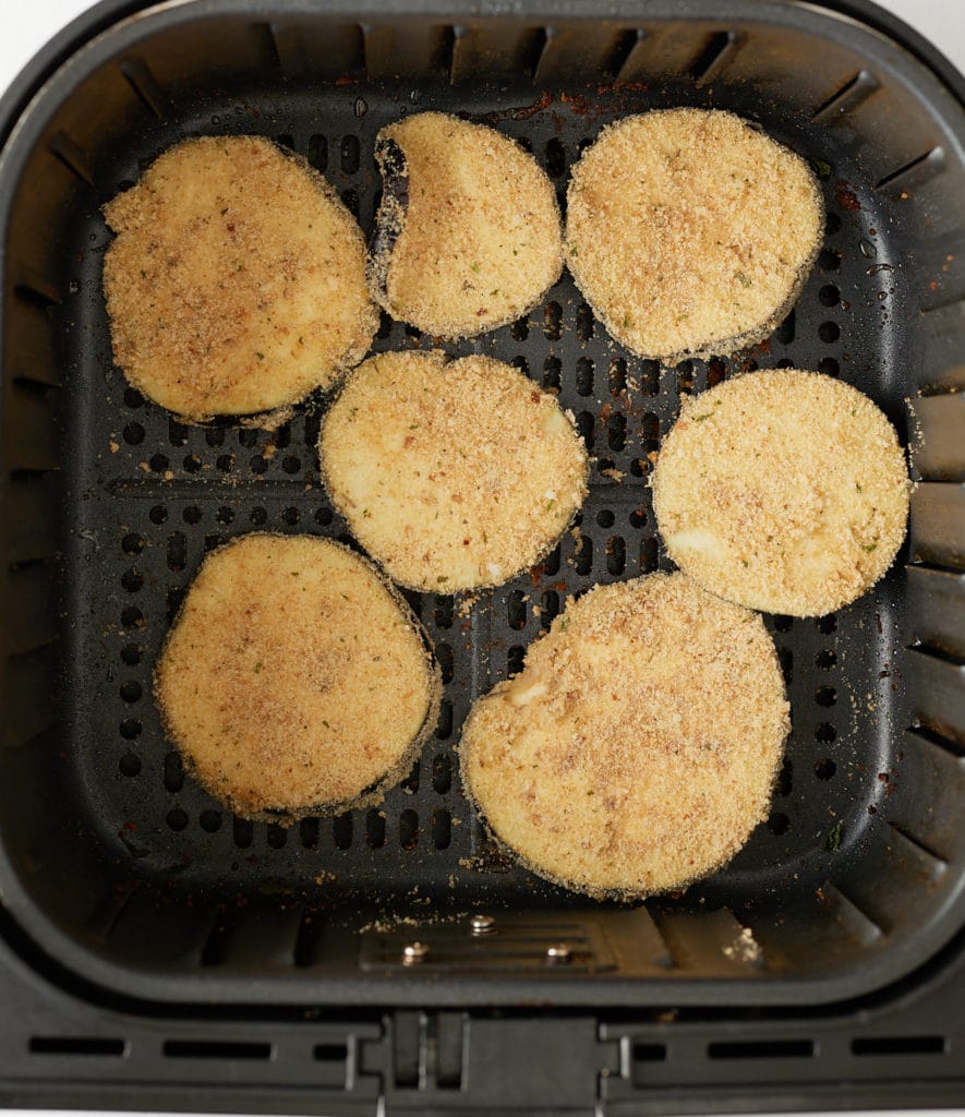 The breaded eggplant slices in the air fryer basket.