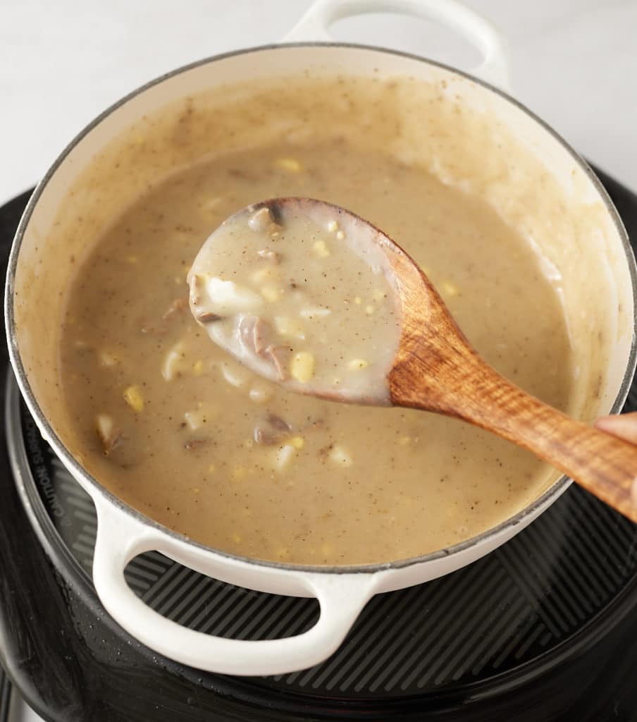 Stirring the giblet gravy with a spoon.