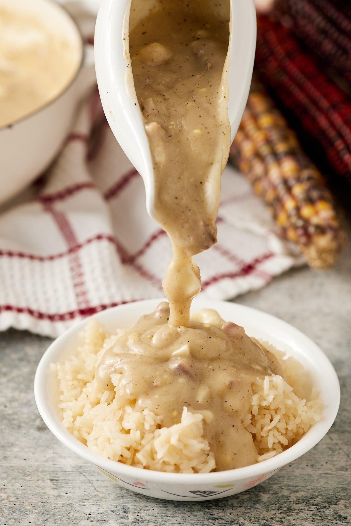 The giblet gravy being poured over mashed potatoes.