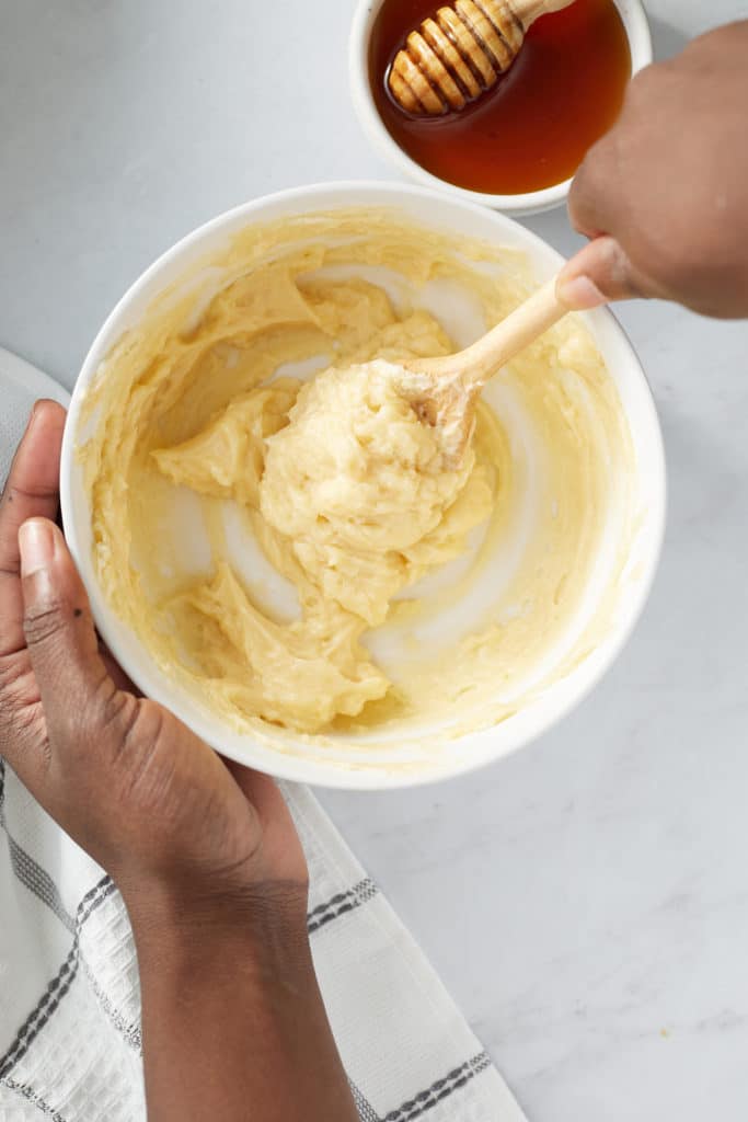 hands stirring honey butter with wooden spoon