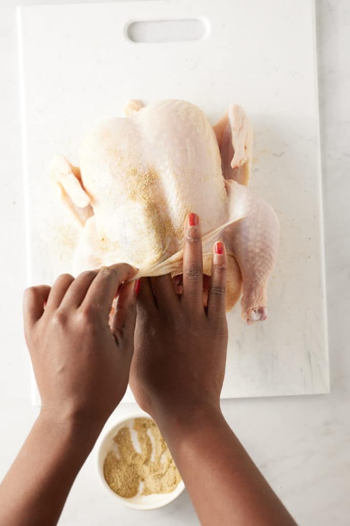 Rubbing the dry mix under the skin of the chicken.