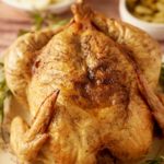 A Thanksgiving chicken served next to fresh herbs.