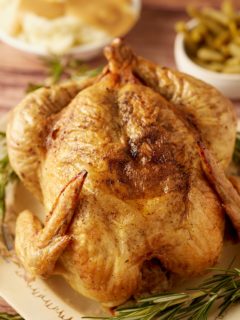 A Thanksgiving chicken served next to fresh herbs.