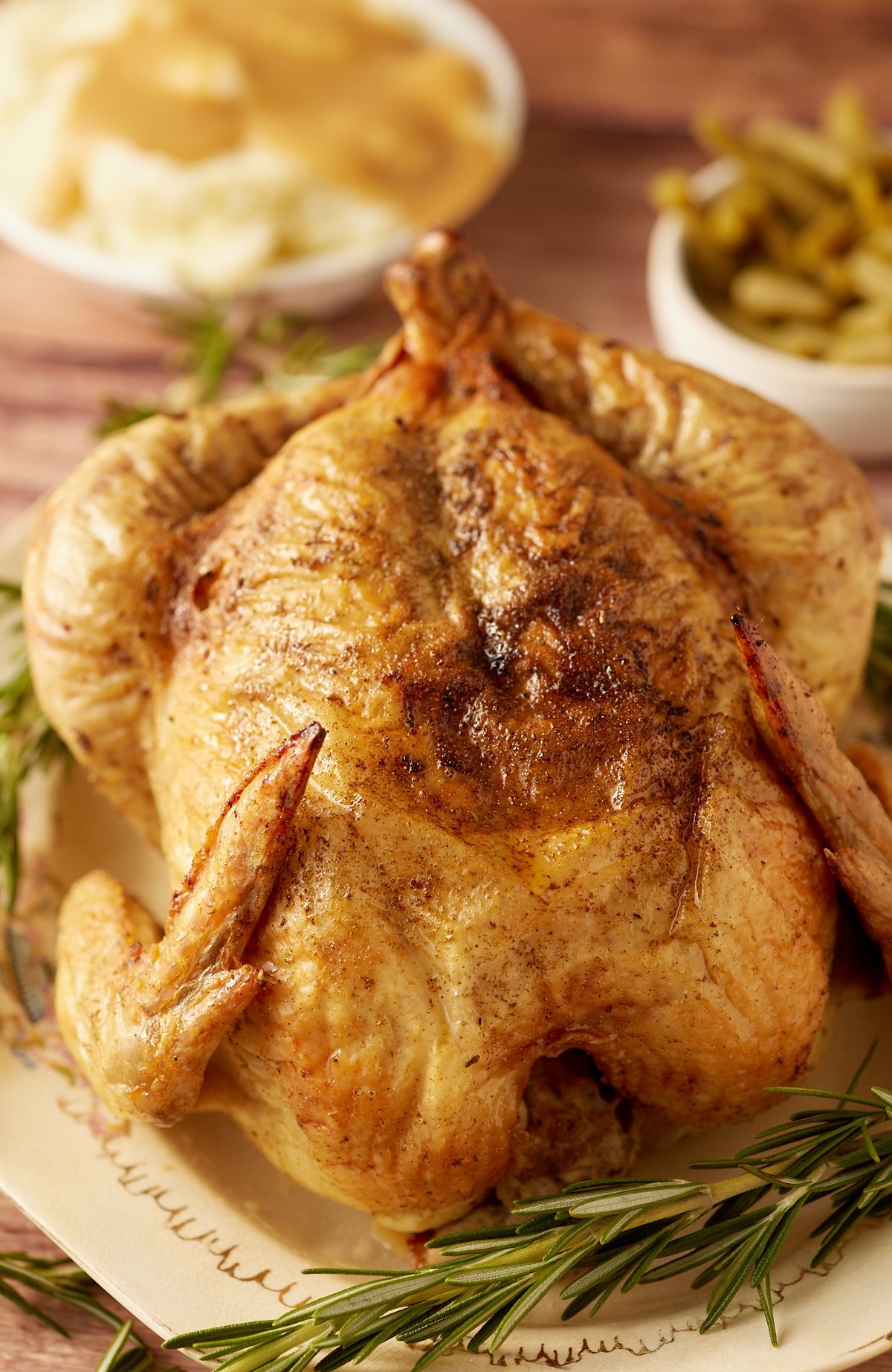 A Thanksgiving chicken served next to fresh herbs.