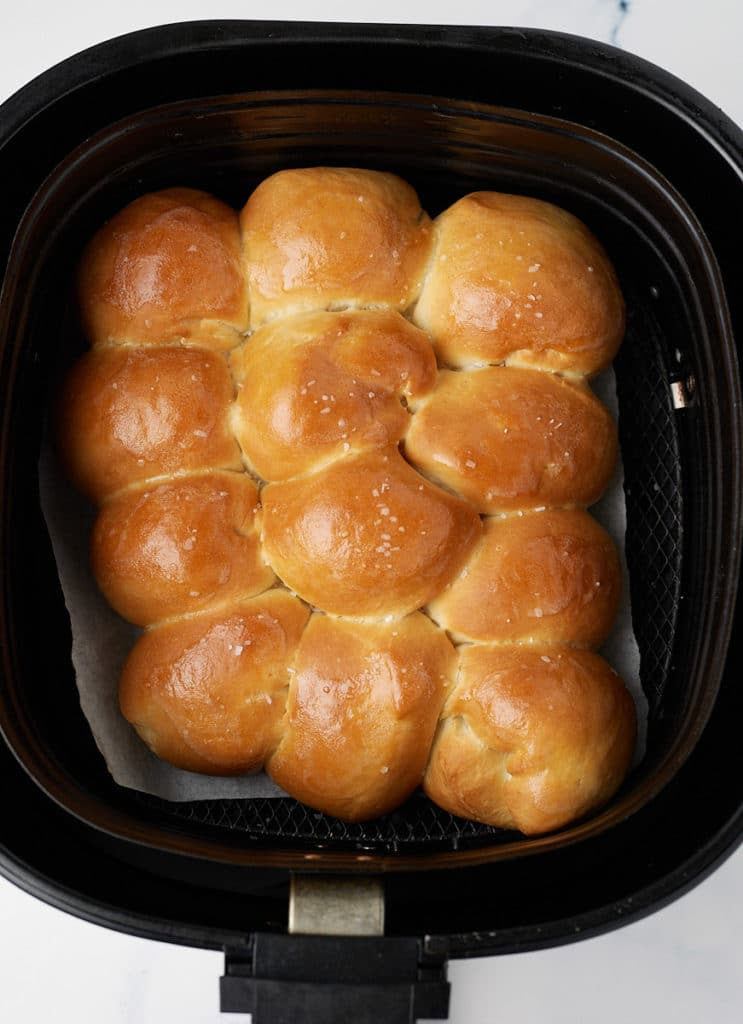 The baked dinner rolls in the air fryer basket.