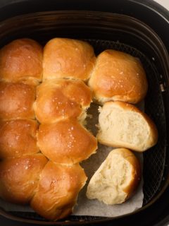 Dinner rolls pulled apart in the air fryer basket.