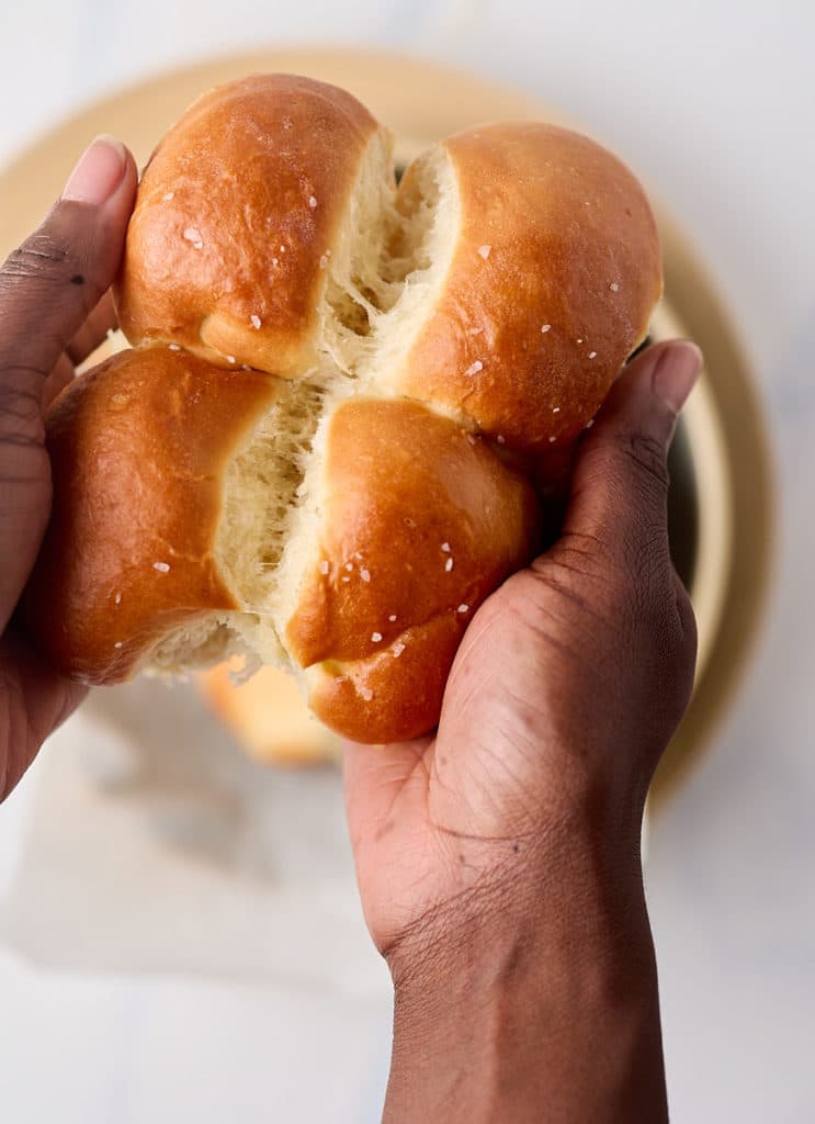 Hands pulling apart the dinner rolls.