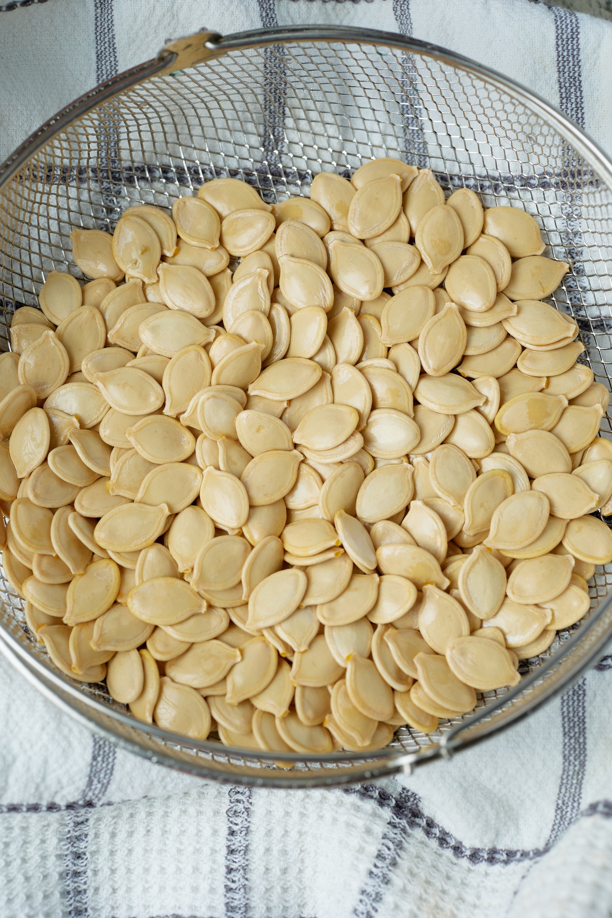 raw pumpkin seeds on colander on towel