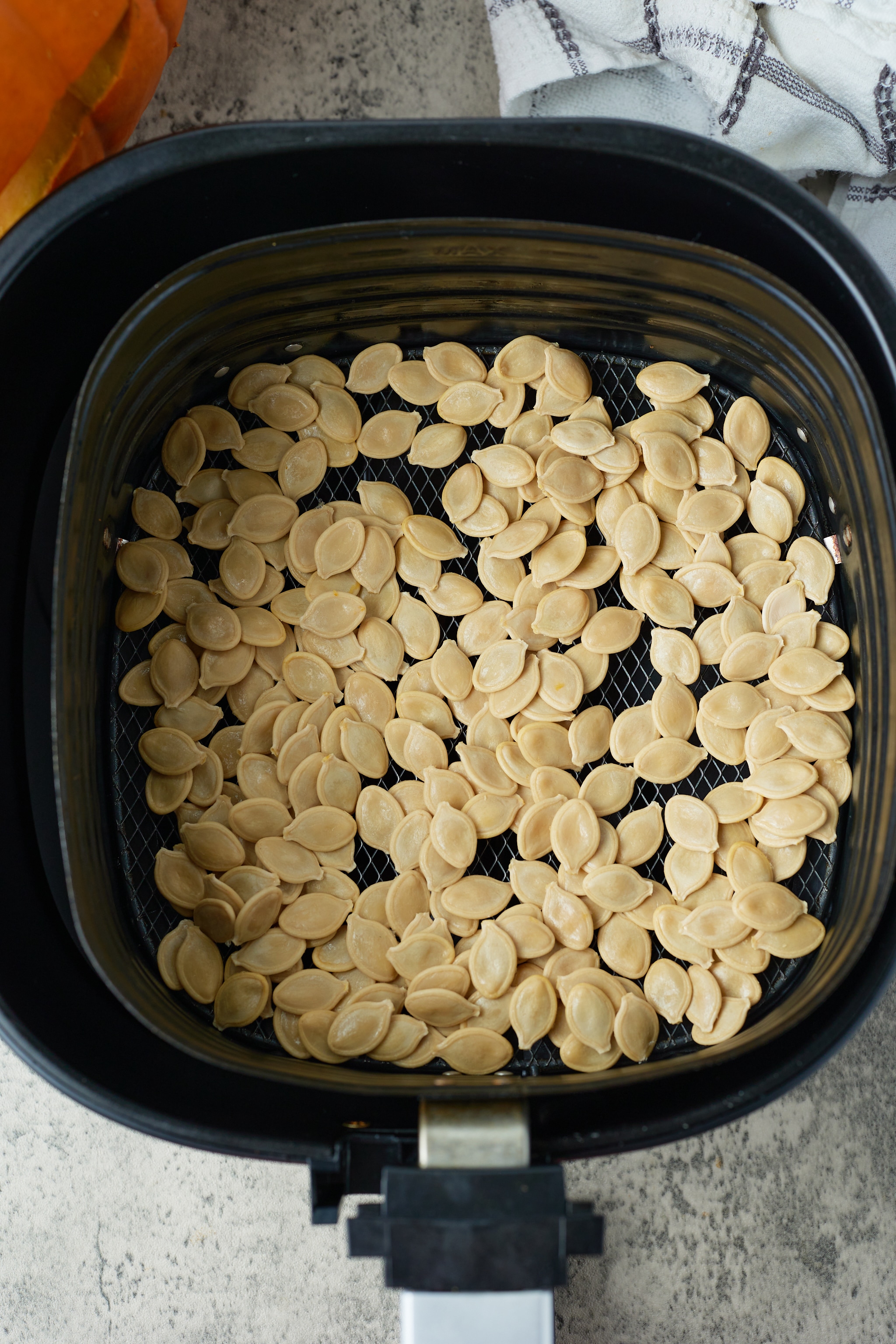 pumpkin seeds in air fryer basket before roasting