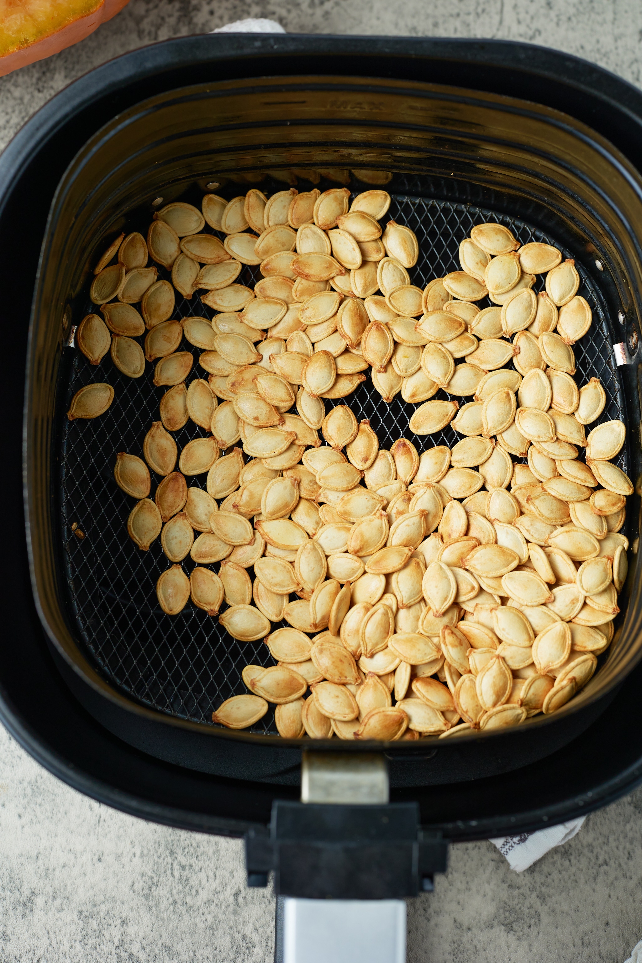 pumpkin seeds in air fryer basket after roasting