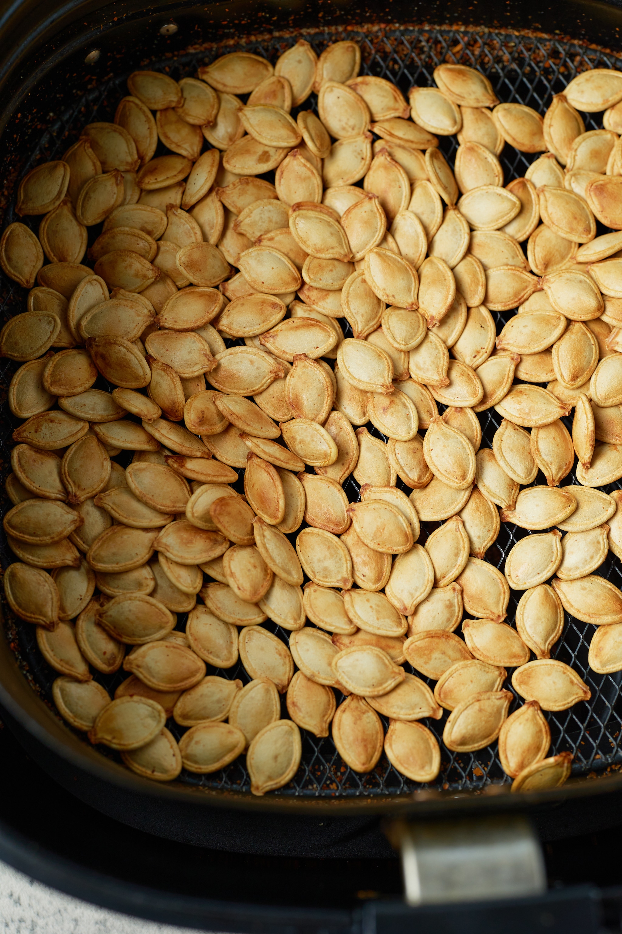 close up photo of roasted pumpkin seeds in air fryer basket