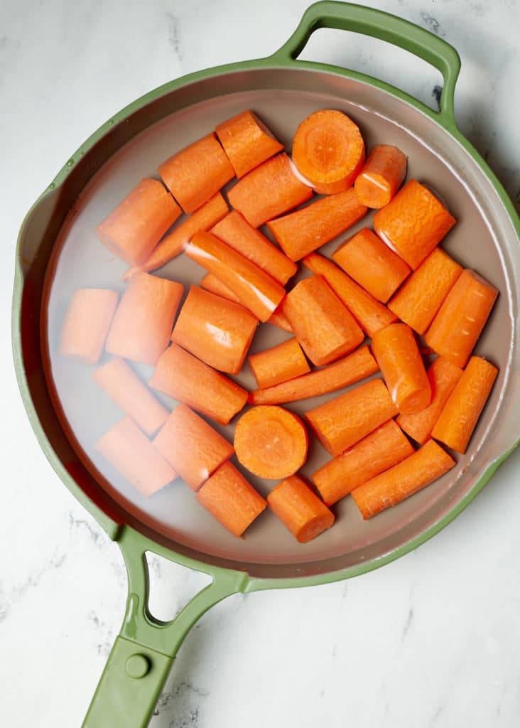 Carrot chunks being cooked in a pan.