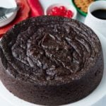 jamaican black cake on table with cherries and drink behind it