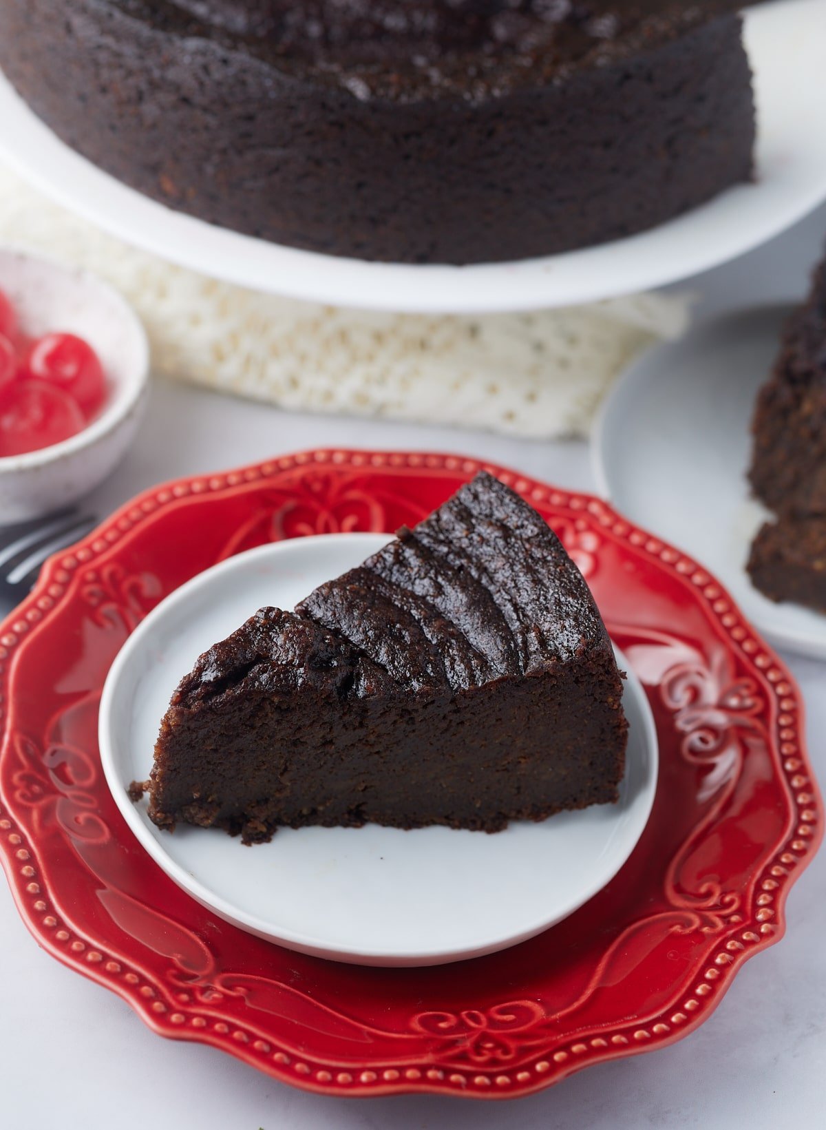 slice of jamaican black cake on plate with whole cake in background