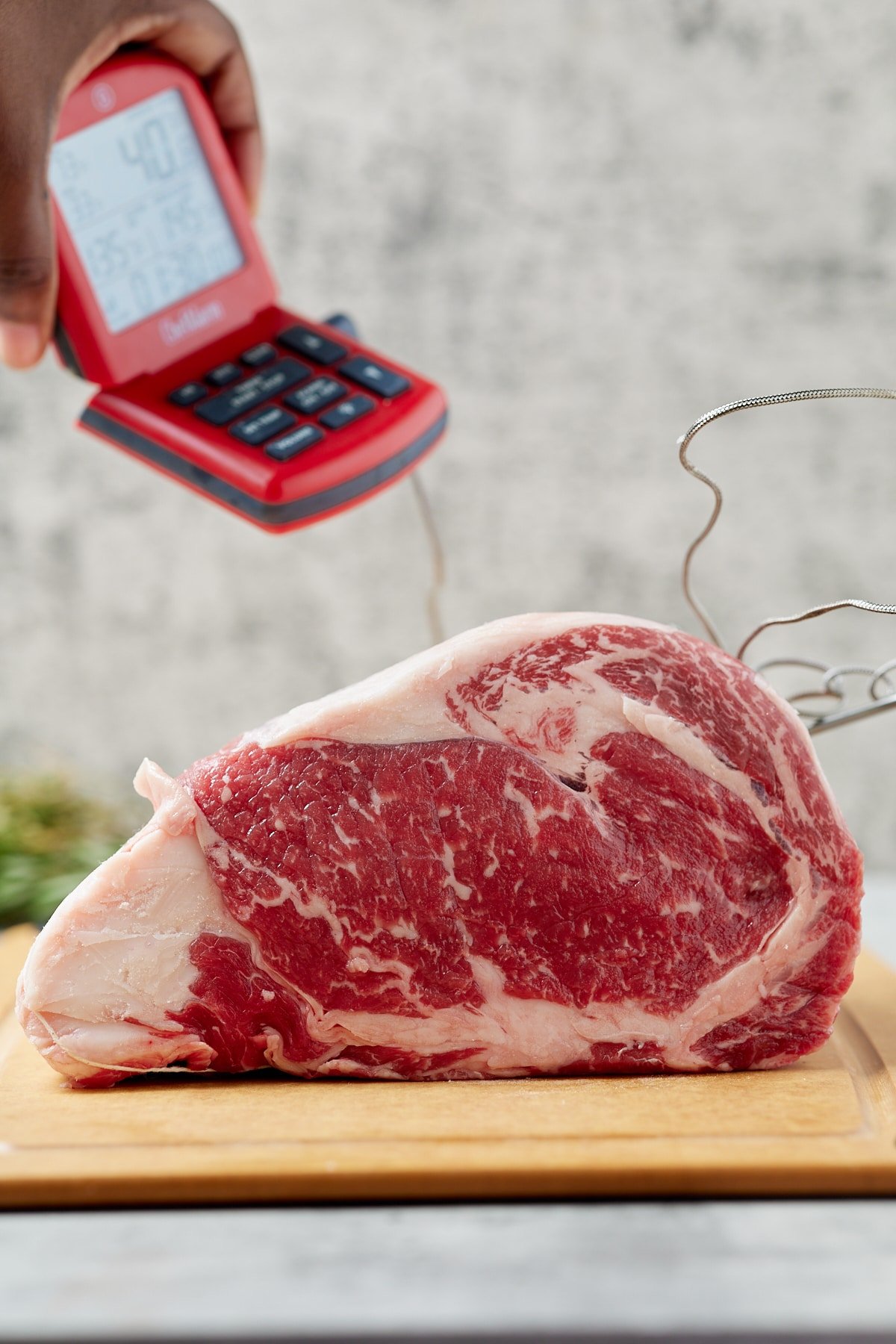 A raw boneless cut of beef with an instant read thermometer.